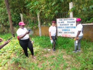 Customs Officers pose by the Bimbia Slave Trade village sign Post.
